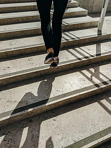person walking on brown concrete stairs during daytime thumbnail