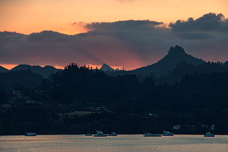 boat on body of water near mountain at golden hour thumbnail