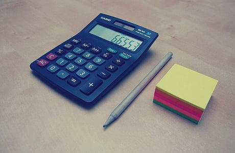 black Casio desk calculator on top of brown surface thumbnail
