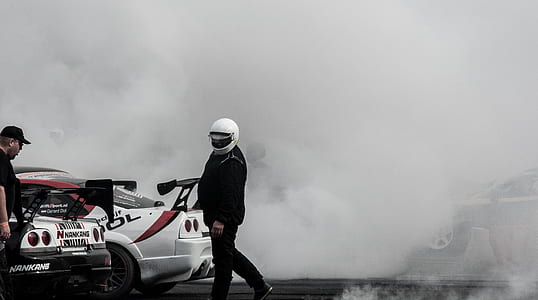 man in black jacket and white helmet near cars thumbnail