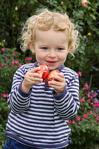 focus photography of toddler holding two red egg packs thumbnail