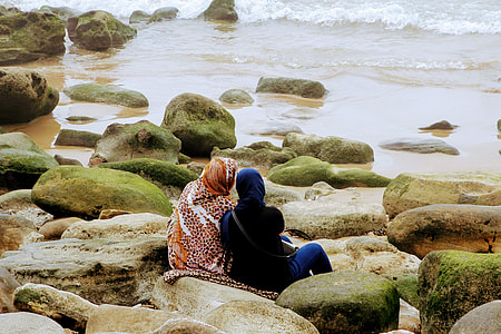 two people sitting on racks near body of water during daytime thumbnail