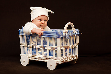 baby wearing white cap riding bassinet thumbnail
