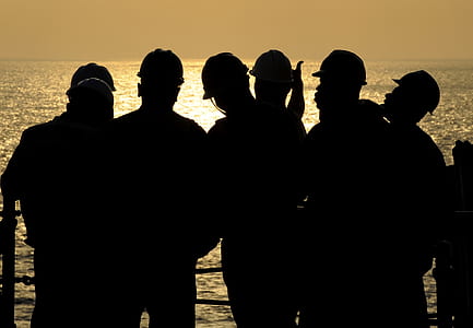 silhouette photography of six men standing on dock beside calm body of water thumbnail