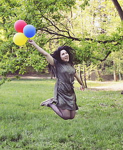 Woman Jumping While Holding Four Balloons thumbnail