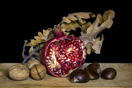 sliced pomegranate fruit on wooden table between onion and nuts thumbnail