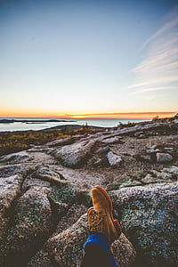 photo of people sitting on rocks near body of water thumbnail