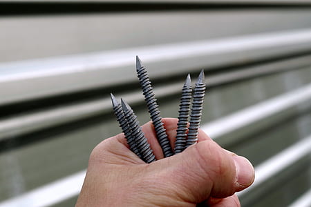 person holding three gray screws thumbnail