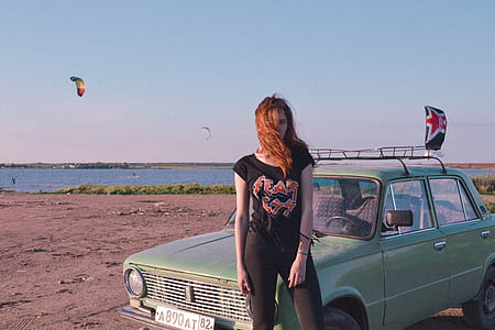 woman standing beside green sedan thumbnail