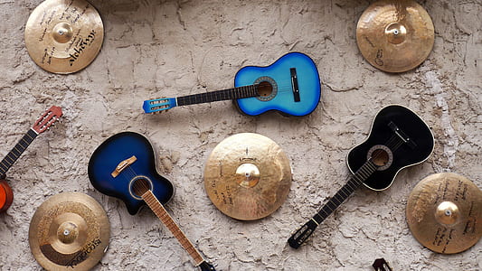 three assorted-color acoustic guitars surrounded with cymbals thumbnail