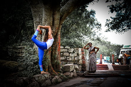 woman stretching legs beside tree during daytime thumbnail