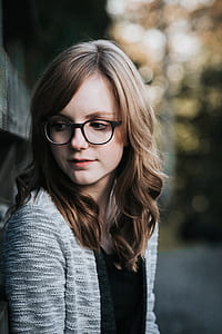 selective focus photography of of woman standing near grey building thumbnail
