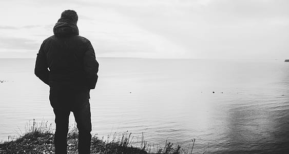 Silhouette of Man Standing Near Body of Water thumbnail