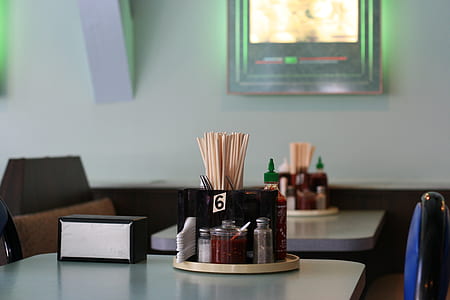 four clear glass condiment shakers on white table thumbnail