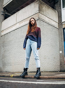 woman in blue and red sweater behind gray wall thumbnail