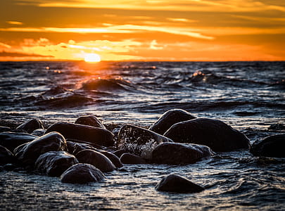 golden hour photography of rock formation in body of water thumbnail