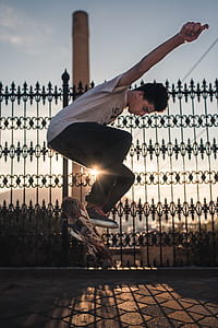 man doing tricks on the skateboard near metal fence thumbnail