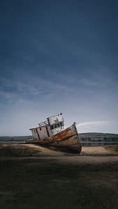white and brown ship on shore under blue and white clouds thumbnail