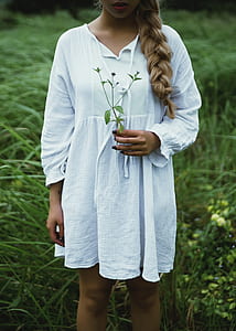 woman holding flower standing on green grass field thumbnail