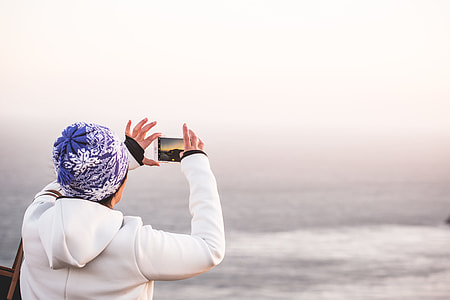 Woman in Winter Hat Taking a Picture of Endless Ocean thumbnail