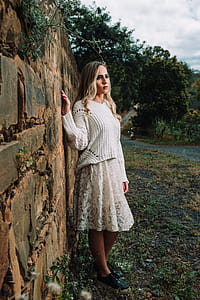 Photo of Woman in White Long-sleeved Shirt Beside Concrete Wall thumbnail