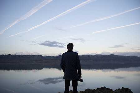 man standing watch calm body of water during daytime thumbnail