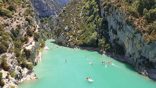 people riding floaters on river between mountains during daytime thumbnail