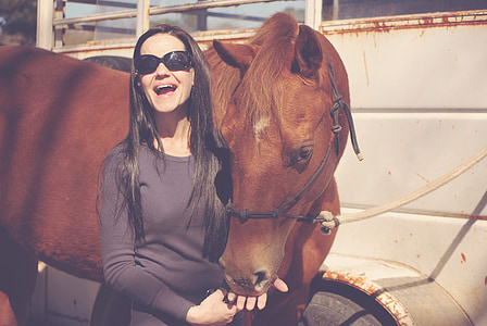 smiling woman standing beside brown horse thumbnail