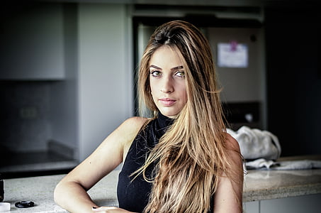 woman wearing black sleeveless top leaning on table thumbnail