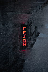 reflection of red Hotel LED signage on the road thumbnail