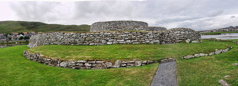 grey ruins surrounded green grass under white sky thumbnail
