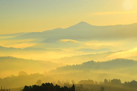 mountains and trees under yellow sky during daytime thumbnail
