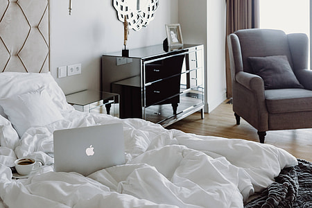 Woman working on a laptop while enjoying a breakfast coffee and chocolate in bed thumbnail