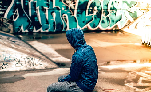 man wearing blue hoodie sitting on skateboard ramp thumbnail