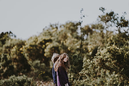 girl and boy standing near bushes during daytime thumbnail