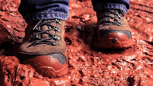 person walking on red mud in closeup photography thumbnail