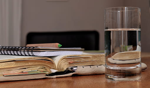 water in clear drinking glass and title book on table thumbnail