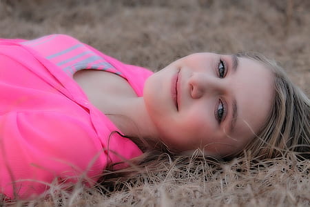 woman wearing pink shirt and lying on brown grassy land thumbnail