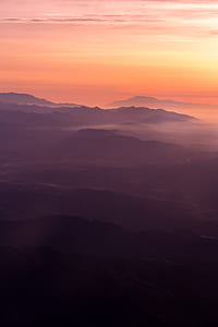 silhouette of mountains covered with fog during golden hour thumbnail