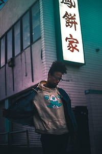 man wearing grey pullover hoodie and black jacket beside building thumbnail