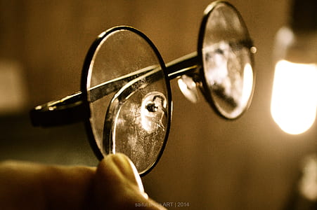 person holding clear eyeglasses with black frames thumbnail