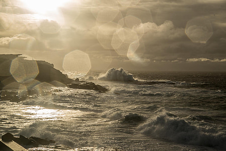 sea wave near rocks under grey sky at sunset thumbnail