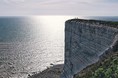 silhouette of two person on cliff of the mountain near body of water thumbnail