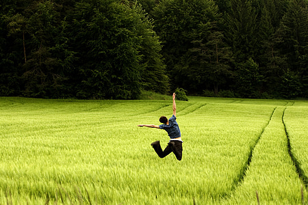 man wears black shirts jumping on green fields near forest during daytime thumbnail