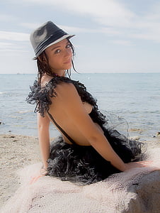 woman sitting on rock formation in front of body of water thumbnail