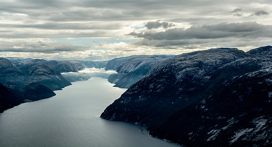 mountain range near body of water under gray cloudy skies thumbnail