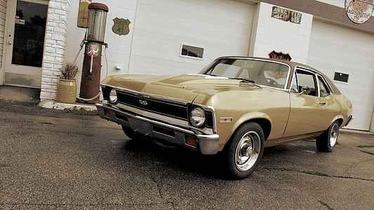 classic yellow coupe parked near white building thumbnail