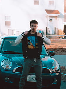 man standing in front of vehicle near building during daytime thumbnail