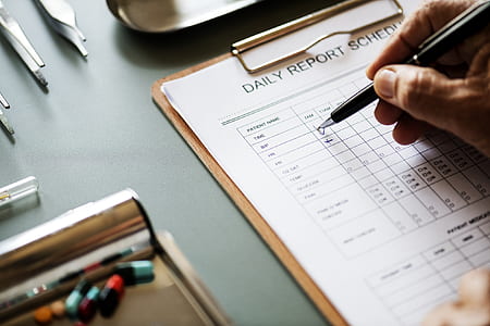 person holding pen and writing on daily report schedule paper thumbnail