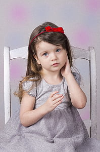 girl in gray cap-sleeved dress sitting on chair thumbnail